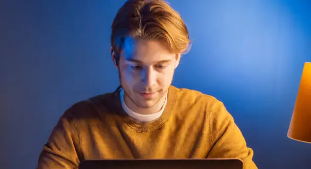 Homem branco de camiseta amarela mexendo no notebook